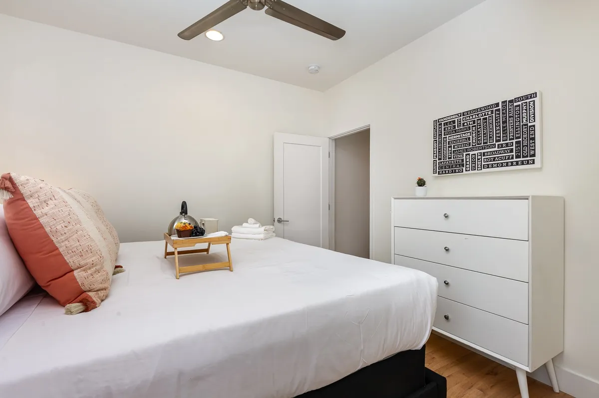 A serene king suite with a plush bed adorned with decorative pillows, a tray with towels and drinks, and soft wall art. The room exudes comfort and privacy, perfect for those seeking a private retreat within a group setting.